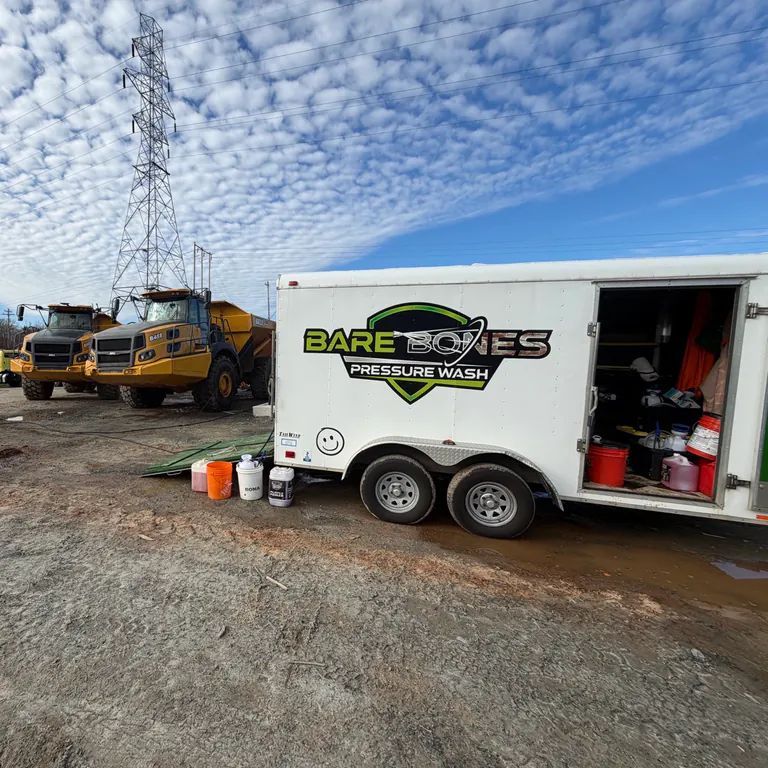Bare Bones Pressure Wash trailer beside heavy equipment under a bright blue sky