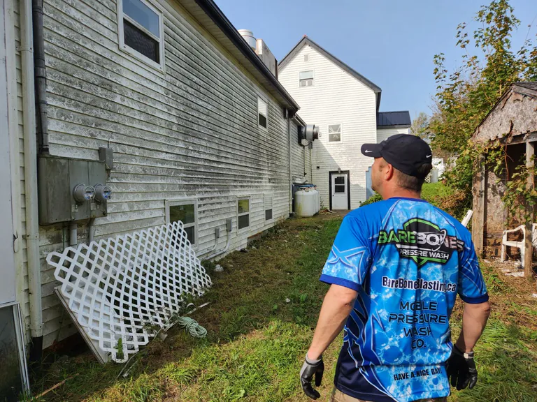 Peter assessing heavy organic buildup on residential siding before choosing the appropriate cleaning method