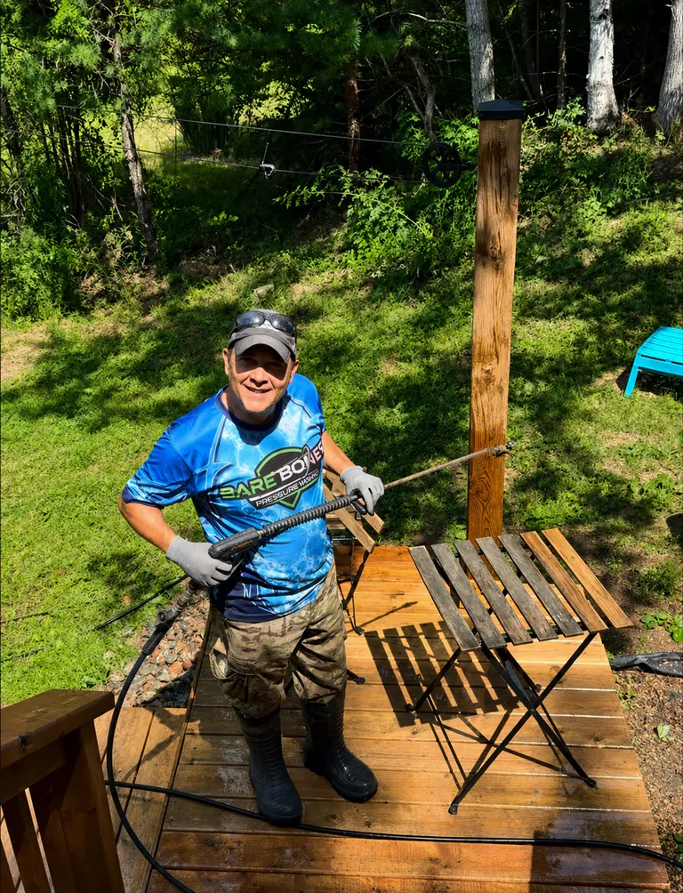 Peter smiling while pressure washing a residential deck in Bare Bones workwear