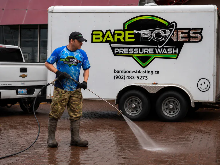 Peter pressure washing beside the Bare Bones service trailer
