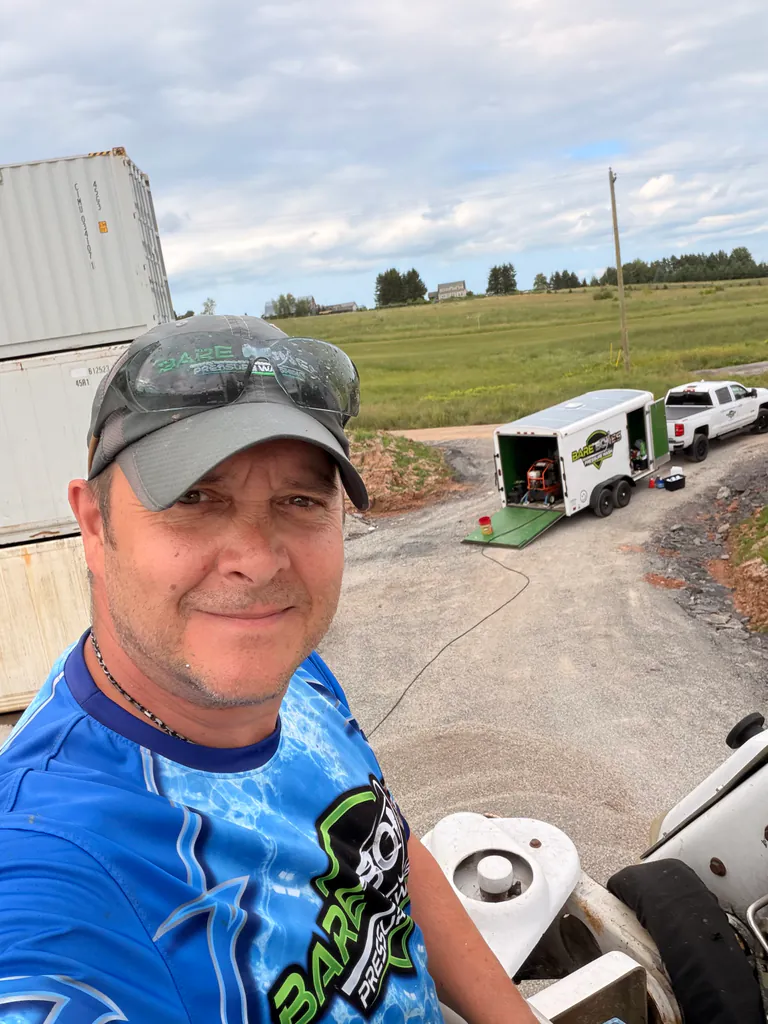 Peter Gant at a Bare Bones Pressure Wash worksite with his service trailer and truck