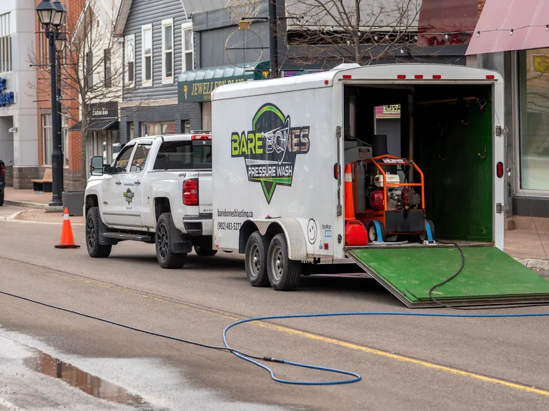 Bare Bones Pressure Wash truck, service trailer, water hoses, and commercial cleaning equipment set up at a downtown worksite